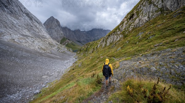 A mountaineer on a hiking trail with lush green vegetation, hiking trail to the Wolayerseehütte,