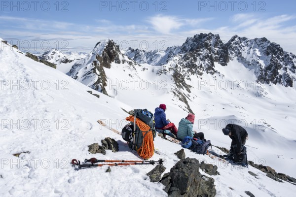 Ski tourers taking a break at the summit, on the Graubünden Haute Route, Scalettahorn, Snow-covered