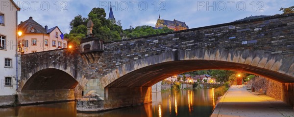 Town view of Vianden with the old stone bridge over the river Our and the castle in the evening,