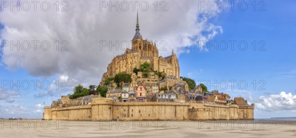 Impressive abbey on an island in the middle of a vast sandy landscape under a blue sky, Le