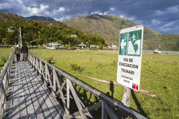 Signpost showing evacuation route in case of a tsunami, wooden boardwalk of Caleta Tortel, Aysen