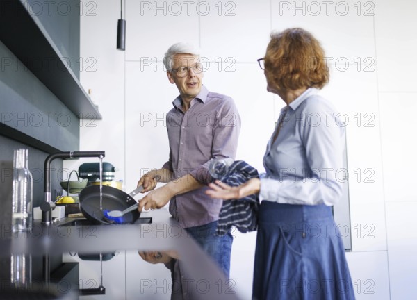 Symbolic photo. An elderly couple stand in the kitchen and do the washing up together. Berlin, 13