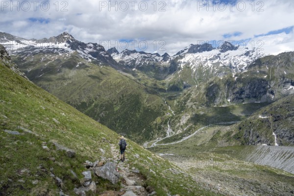 Mountaineer on a hiking trail in front of a picturesque mountain landscape, rocky mountain peaks