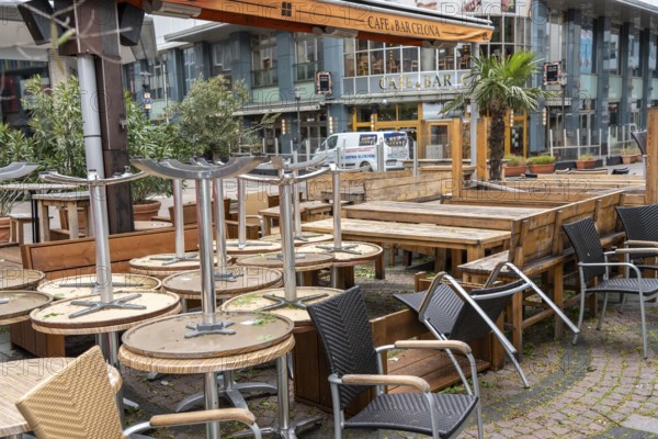 Stacked chairs and tables from various catering establishments, on Kennedyplatz, closed cafes,