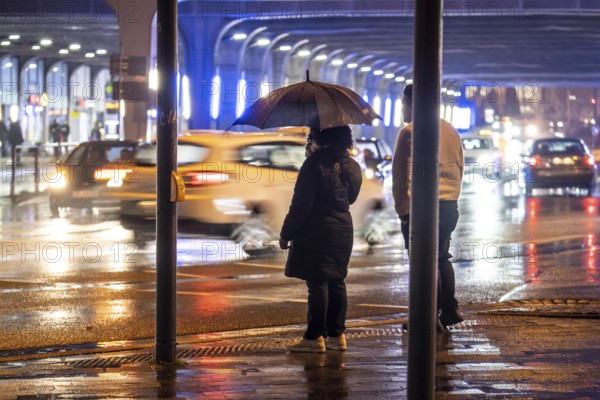 Illuminated subway at the main railway station, pedestrians at a pedestrian crossing, rainy