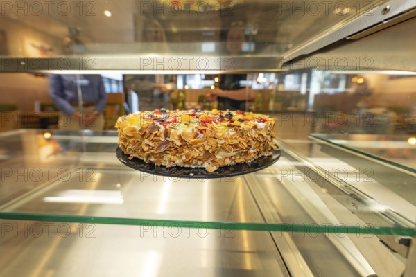 An artistically decorated cake with almond slivers and fruit in a glass display case, Cafe Kuh,