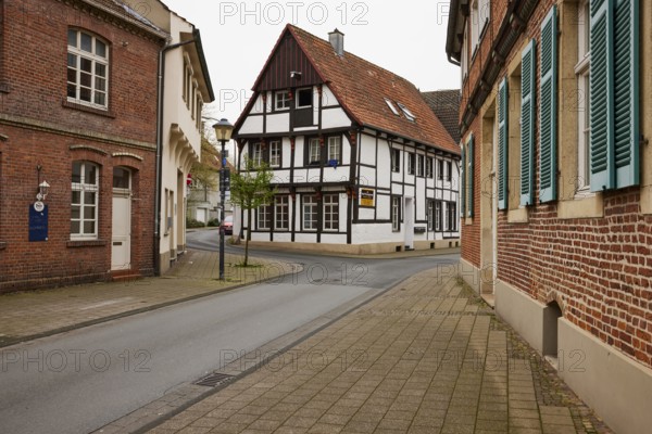Historic brick houses with white windows and shutters and a small half-timbered house in Warendorf,