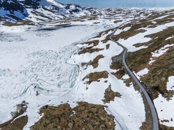 Aerial view of mountain crossing Sognefjellsvegen, along frozen lake Prestesteinsvatnet,