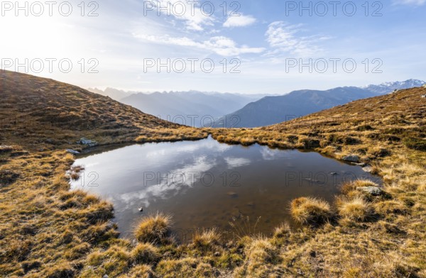 Small mountain lake on the Krahberg, sun star in the morning, mountain panorama in autumn, Venet