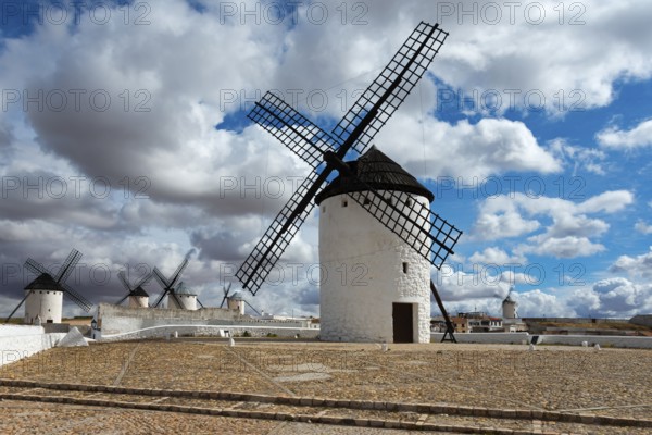 Row of white windmills on a sandy ground with a cloudy sky, Campo de Criptana, Ciudad Real