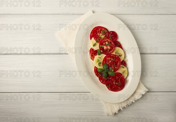 Caprese salad, Italian traditional dish, tomatoes with mozzarella cheese, basil and spices, top
