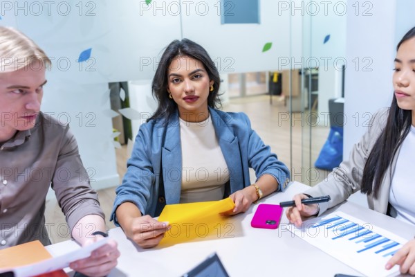 Multi ethnic business team collaborating on project in modern coworking space, analyzing financial