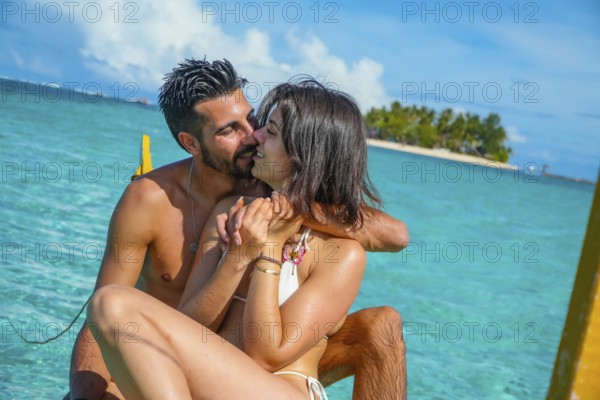 Romantic couple enjoying a kiss while relaxing on a traditional banca boat in the clear turquoise