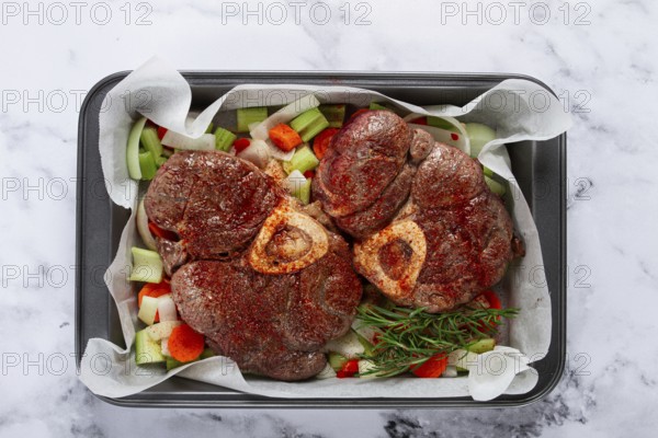 Fried meat on the bone, raw, chopped vegetables, ingredients in the oven, for cooking ossobuco, top