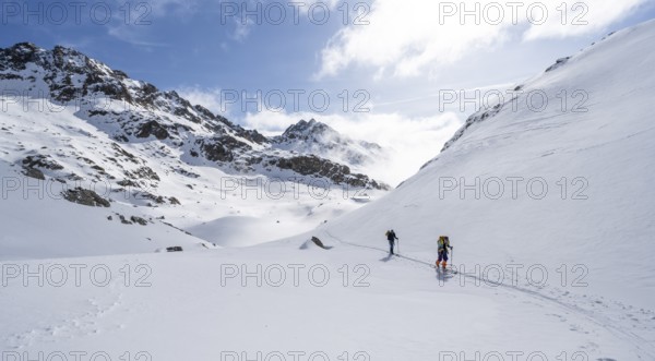 Atmospheric clouds in a wintry mountain landscape, ski tourers on the ascent to Porta d'Es-cha,