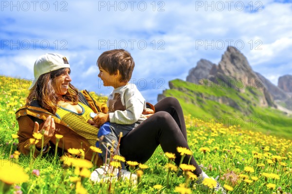 Tourists relaxing in a dandelion field, enjoying the view of the seceda mountains in the italian