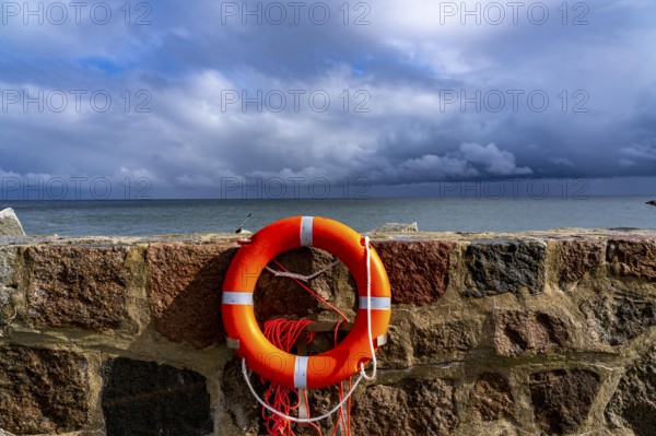 The city harbour of Sassnitz, island of Rügen, pier, harbour dam, dark rain clouds, lifebuoy,