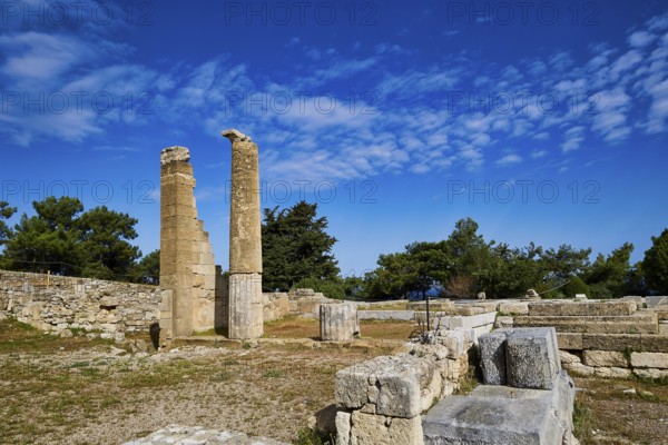Two ancient columns amidst ruins and stone walls under a clear blue sky, Temple of Apollo, Kamiros,