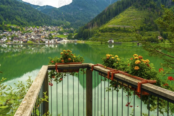Wooden balcony with flower boxes overlooking the picturesque village of alleghe, reflecting on