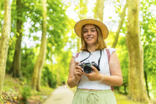 Portrait of a caucasian female young photographer standing in the forest smiling at camera and