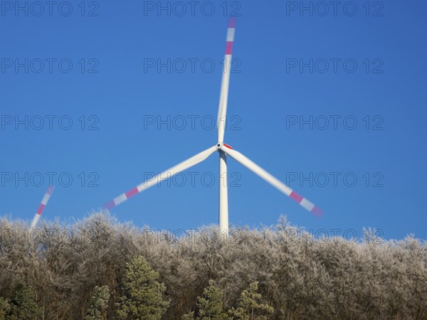 Wind turbines, in the middle of a hoarfrost covered forest, beside Zierenberg in the winter,