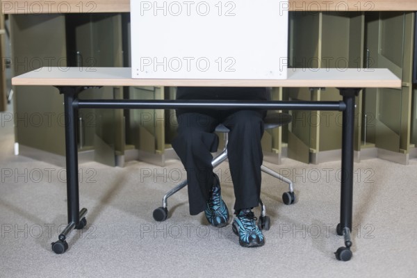 A person sits in a polling booth during voting for the election to the 21st Bundestag at the IHK