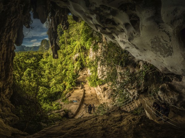 Photo of greenery and cave famous for paintings of wild animals and hand markings with petroglyphs