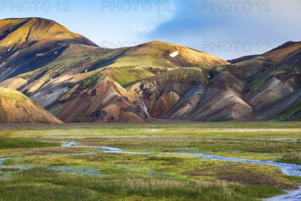 Green Valley is flooded with melt water. Snow lies in the hollows of colorful rhyolite mountains.