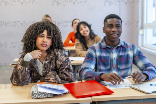 Multi ethnic students sitting at desks in a classroom, engaging with the teacher and absorbing