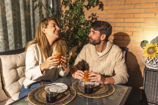 Smiling man and woman sharing a meal of burgers and drinks, creating a warm and intimate atmosphere