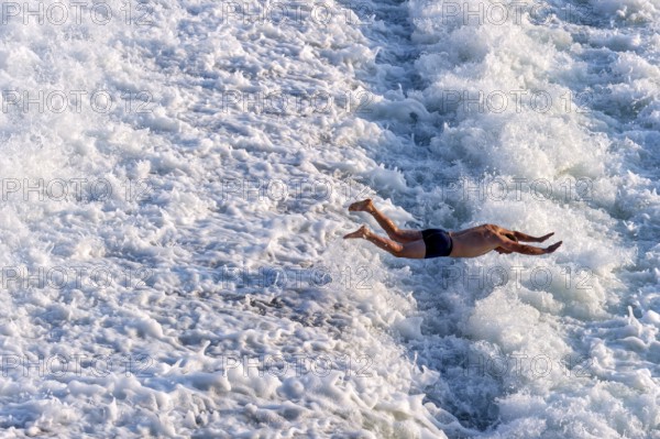 Man bathing in the spray of the Lech weir, jumping into the white foaming water of the cascades,