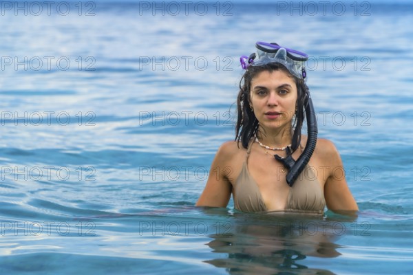 Young woman wearing snorkeling gear, swimming in the crystal clear waters of white beach, moalboal,