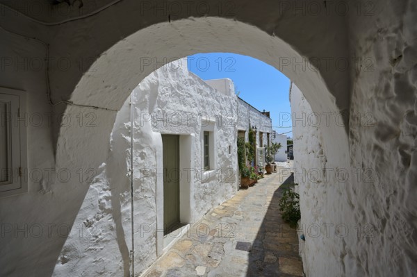 Round arch and whitewashed façade of a historic building with a cobblestone path and potted plants