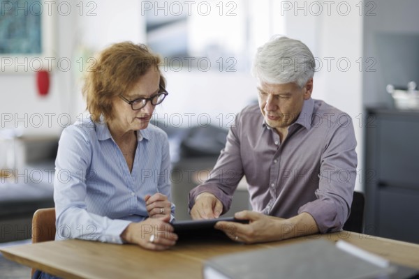 Symbolic photo. A woman and a man sit together at a table with a tablet and talk. Berlin, 13.08