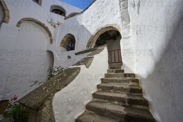 Stone staircase in a historic building with white walls and stone arches on a sunny day, Inside the