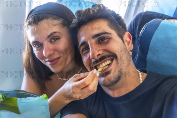 Young woman feeding french fry to her boyfriend while traveling by plane to coron island,
