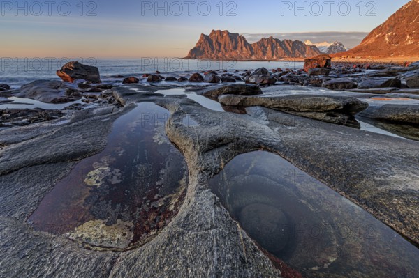 Rocky coast in front of steep mountains in the evening light, winter, the eye, Utakleiv,