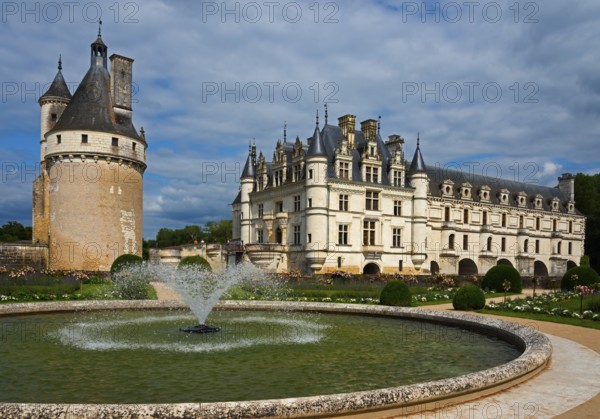 Castle with round tower and fountain in a well-tended garden under a blue sky, Chenonceau Castle,