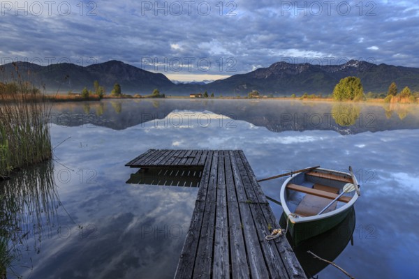 Mountains reflected in lake, jetty and boat, morning light, spring, Loisach-Lake Kochel moor,