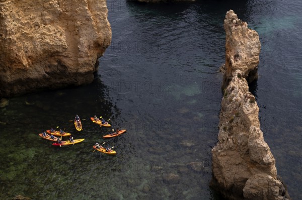 Kayaker, kayaks, kayaking, guided tour through grottos, rocks in the sea, Ponta da Piedade, Lagos,