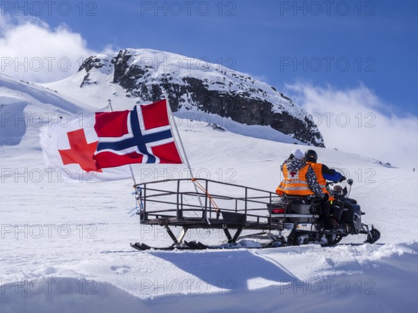 National day 17th May, snowscooter, norwegian flag, near Finse, glacier Hardangerjøkull, Hardanger,