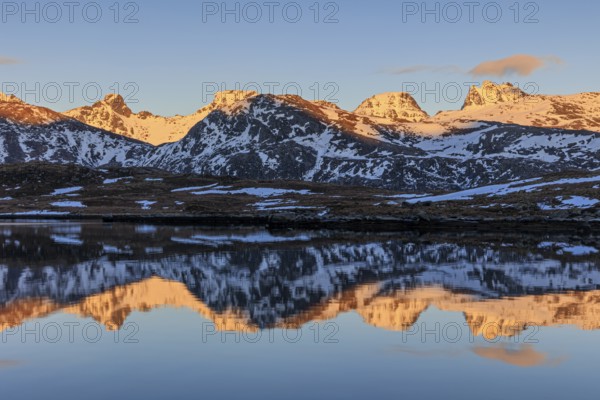 Steep mountains reflected in fjord, evening light, snowy, winter, Moskenesoya, Lofoten, Norway,