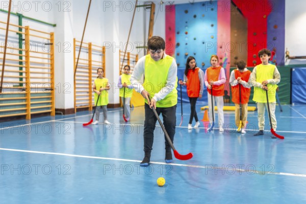 Group of preteen students wearing bibs, actively playing floorball during gym class in a lively