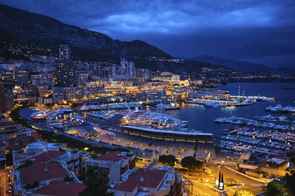 Aerial view of Monaco Monte Carlo harbour and illuminated city skyline in the evening blue hour