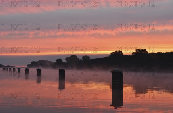 Jetty, dolphins, ship's switch at sunrise and fog on the Kiel Canal, Schleswig-Holstein, Germany,