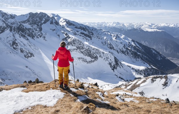 Ski tourer standing next to summit cross, summit of Mitterzeigerkogel in winter, Sellraintal,