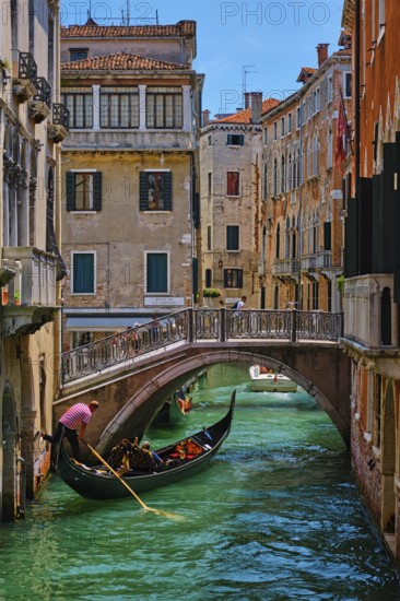 VENICE, ITALY, JULY 19, 2018: Narrow canal between colorful old houses with gondola boat with