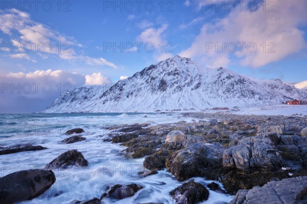 Beach of Norwegian sea on rocky coast in fjord on sunset in winter. Vareid beach, Lofoten islands,