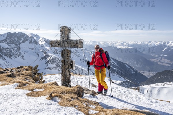 Ski tourers at the summit of the Mitterzeigerkogel with summit cross in winter, Sellraintal,