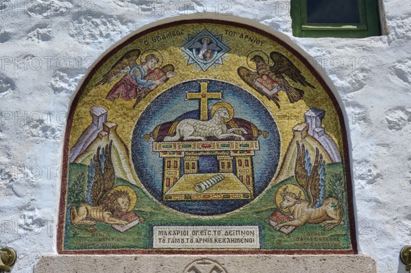 A religious mosaic with Christian symbols and angels, decorating a stone wall in a Catholic church,